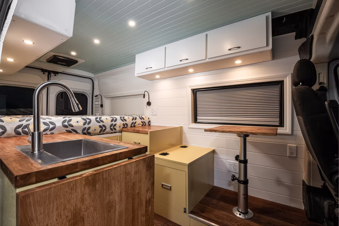 Campervan interior with full kitchen and wood cabinetry