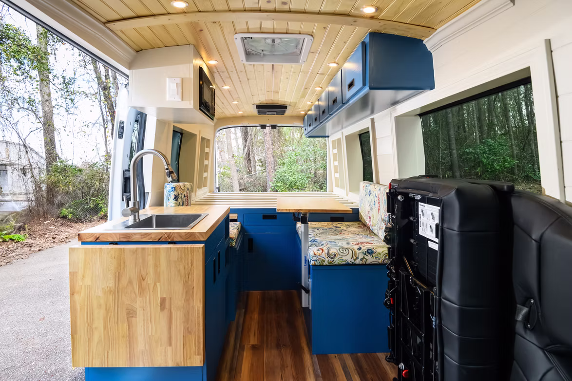 Campervan bed area with warm wood panelling